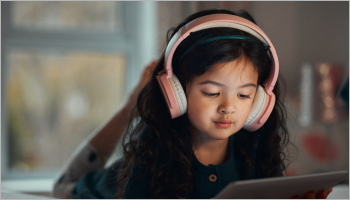 Girl with pink headphones looking at a screen