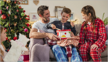 Man and woman smiling at a boy holding a present